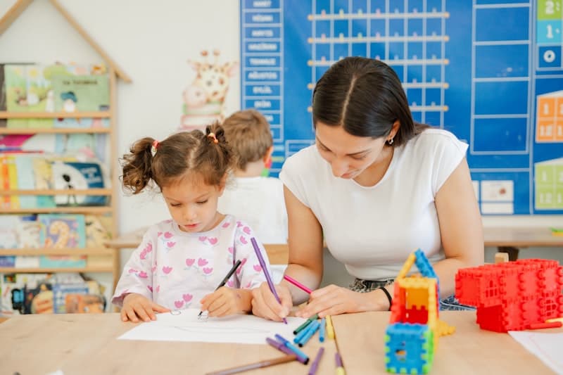 Teacher and child drawing together at a table
